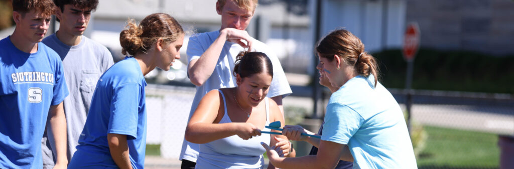 Students wearing blue t-shirts participating in a teamwork event outside